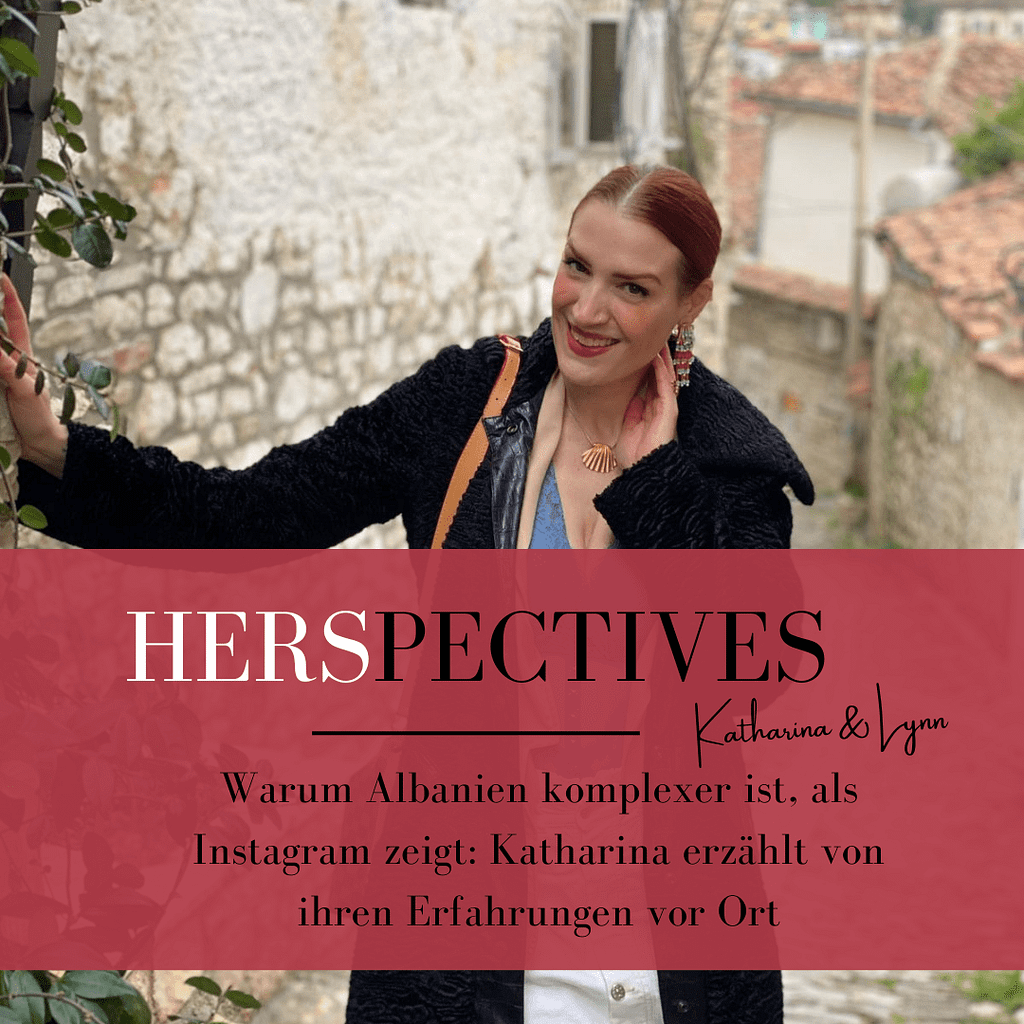 Frau mit rotem Haar und schwarzem Mantel lehnt an einer Steinmauer in einer Gasse mit alten Häusern im Hintergrund, darüber rotes Textfeld mit dem Schriftzug 'HERSPECTIVES Katharina & Lynn Warum Albanien komplexer ist, als Instagram zeigt Katharina erzählt von ihren Erfahrungen vor Ort'